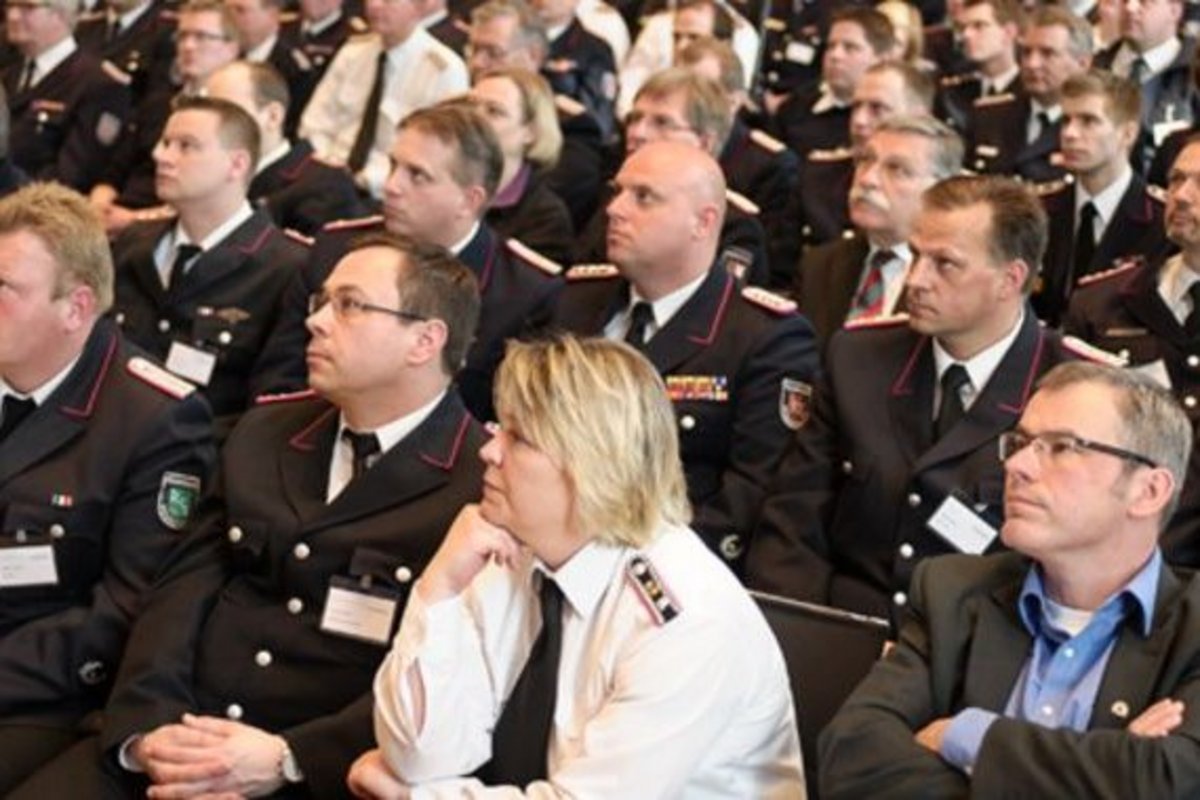 mehrere Feuerwehrleute sitzen in Uniformen